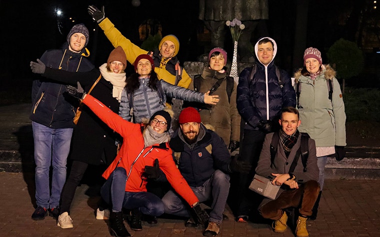 A group photo of the Enlight CMF team standing outside. They are smiling at the camera with their arms open.