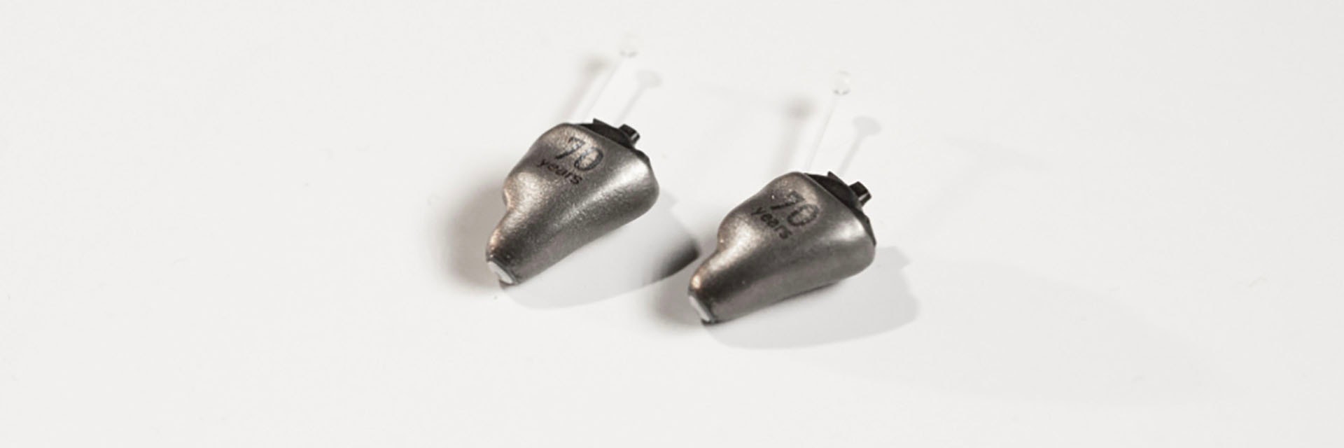 Metal 3D-printed hearing aids with '70 years' etched in the material