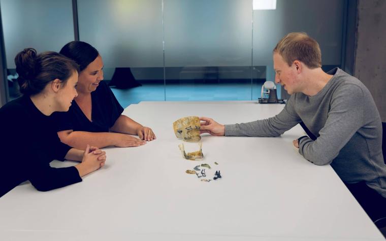 Three people sitting at a table discussing 3D-printed anatomical models