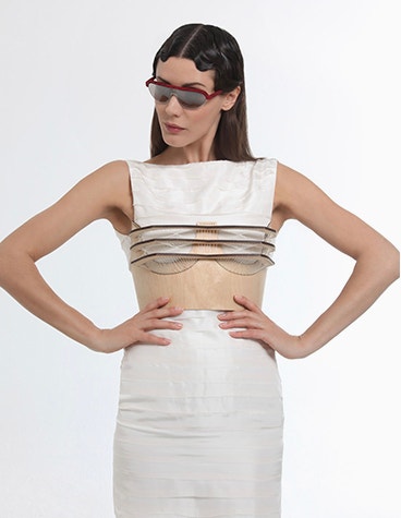 Weißes weibliches Model posiert mit den Händen in den Hüften und trägt eine rote Hoet Cabrio-Sonnenbrille.