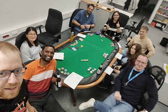 Materialise Germany team sitting around a poker table smiling with one team member holding the camera for a selfie