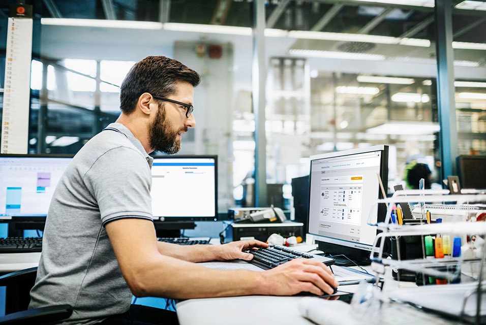 Hombre sentado en un escritorio utilizando un software en un ordenador