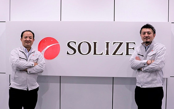 Two SOLIZE team members standing next to a SOLIZE sign.