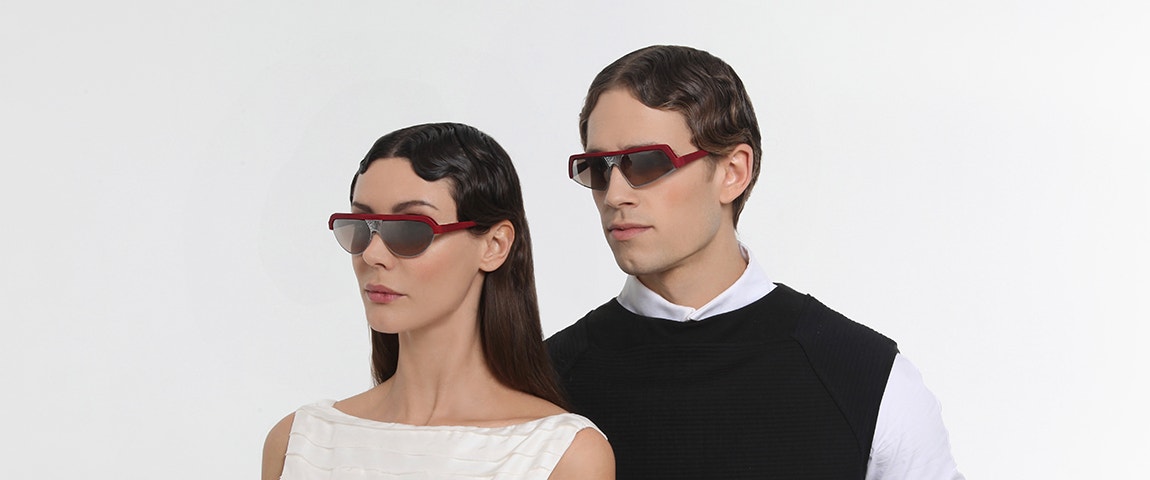 Männliche und weibliche Models mit gewelltem Haar, die in die gleiche Richtung schauen und eine rote Hoet Cabrio-Sonnenbrille tragen.