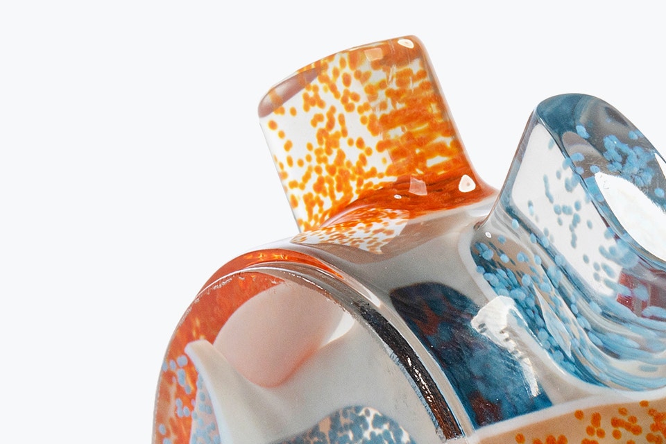Obenaufnahme eines 3D-gedruckten statischen Mischers, größtenteils transparent mit einigen orangen und blauen Partikeln im Inneren