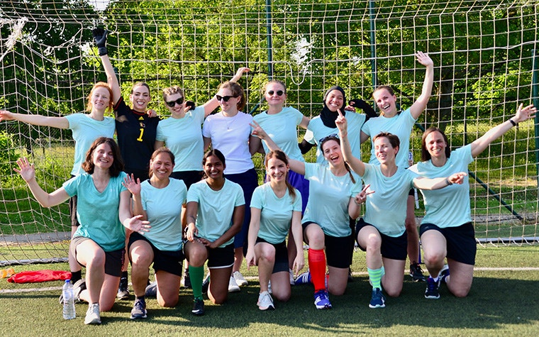 All-female Materialise HQ soccer team smiling and waving