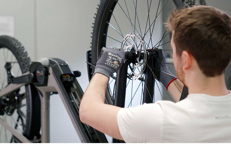 Man checking a bicycle wheel as the bike hangs upside down