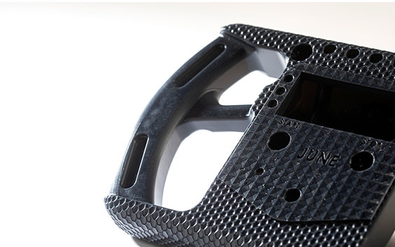 Close up of a black 3D-printed racing-style steering wheel made in Taurus using stereolithography.