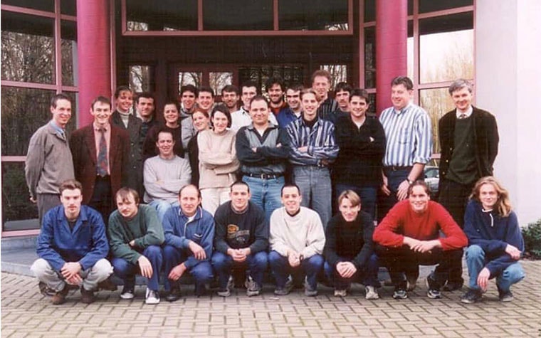 A group of early Materialise employees posing outside of a building