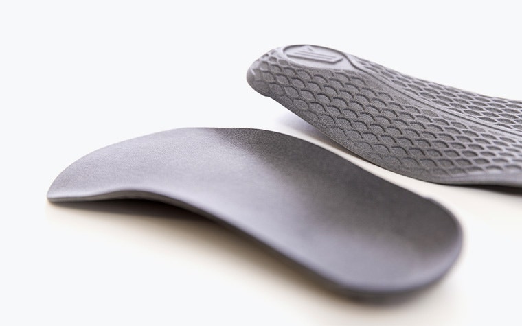 A pair of gray 3D-printed insoles made in PA 11 using Multi Jet Fusion.