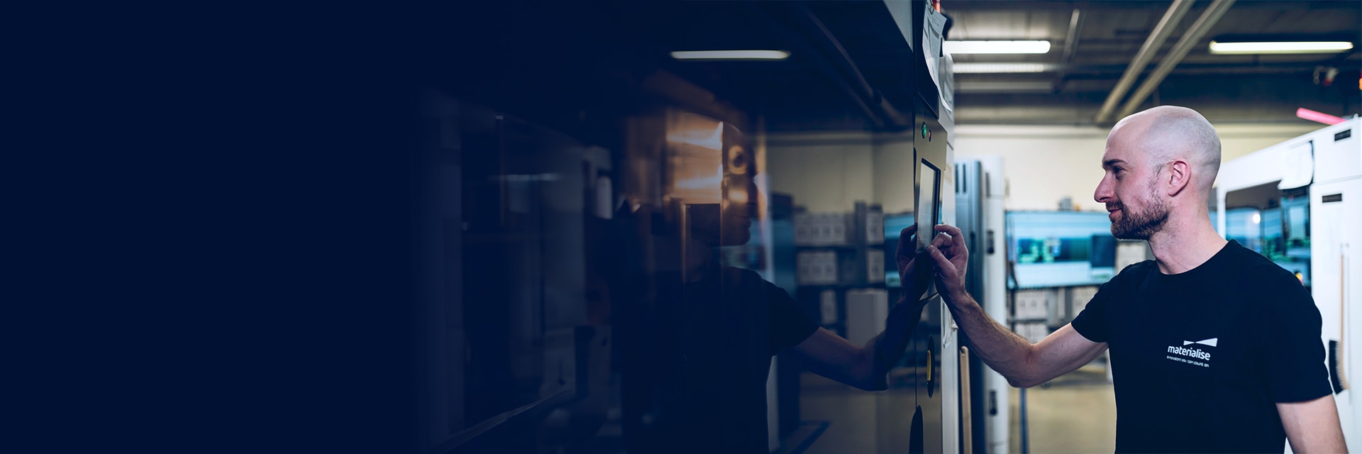 Materialise employee in a production area, operating the control panel of a 3D printer