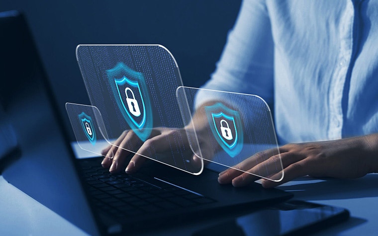 Person with their hands on a laptop and graphics of secure locks floating in front of the computer
