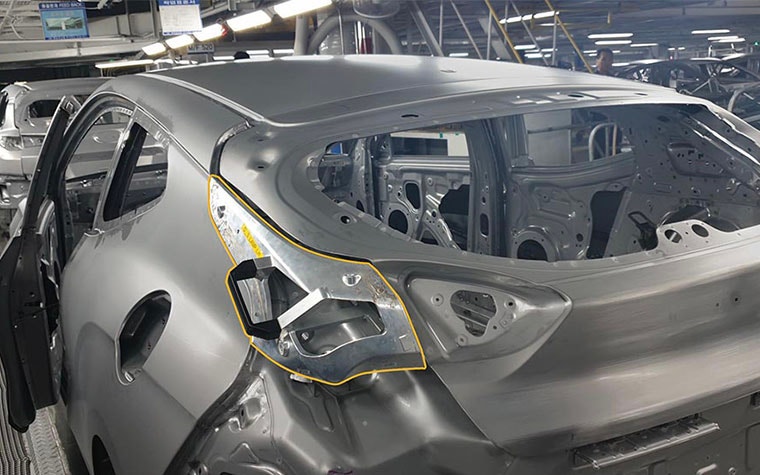 Car in production with jig in place and highlighted with yellow