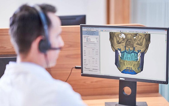 A clinical engineer looks at a 3D software image of human skull on his computer screen 