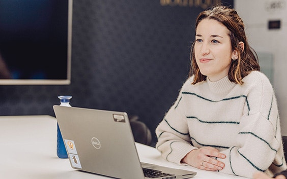 Woman smiling while sitting at a computer with her arms crossed on a desk