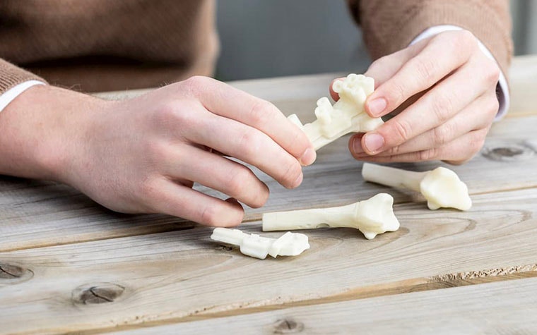 Man holding 3D-printed surgical guides and a wooden table