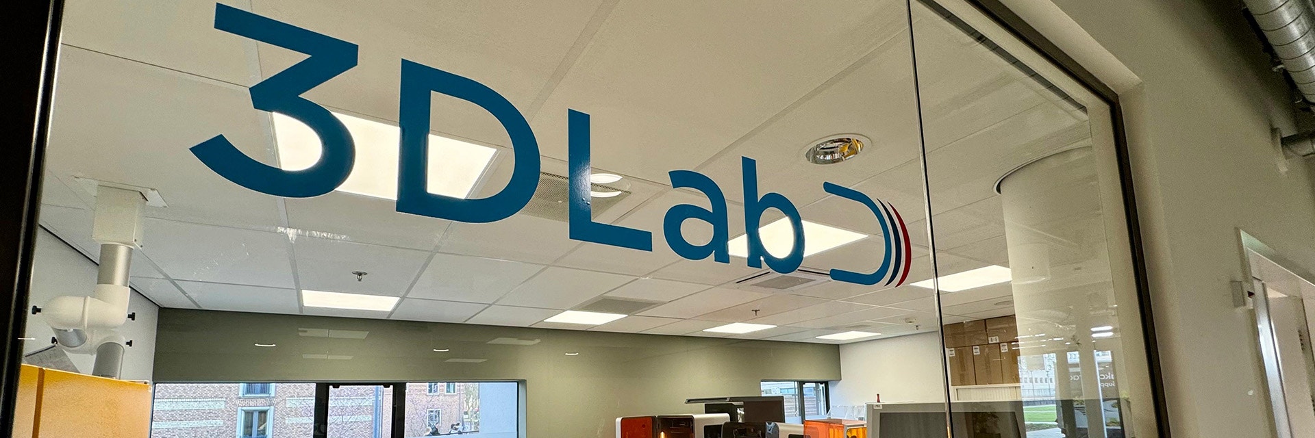 The words '3D Lab' on a glass wall at the entrance of Radbound University's 3D lab