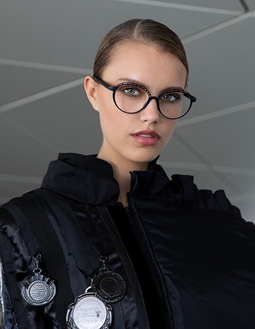 Primo piano di modella che guarda nella fotocamera indossando occhiali dalla montatura nera della collezione Hoet Cabrio PR