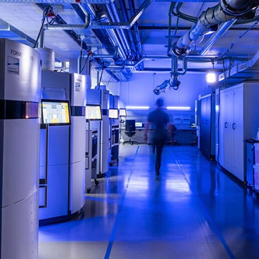 Imagen borrosa de una persona caminando a través de una planta de producción de impresión 3D