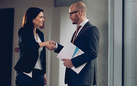 Two people shaking hands in formal business outfits