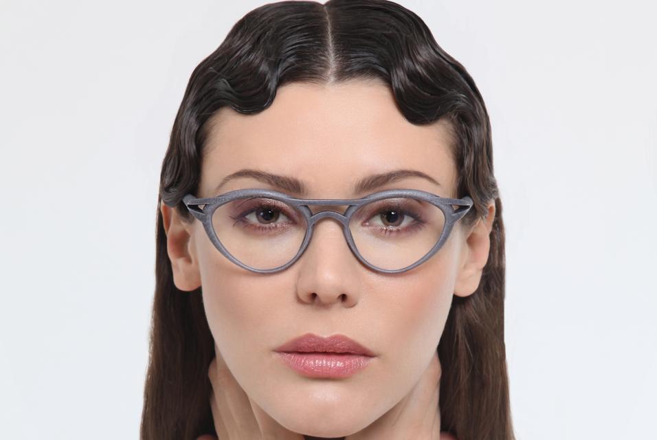 Model with wavy hair wearing gray eyeglasses with the Luxura finish