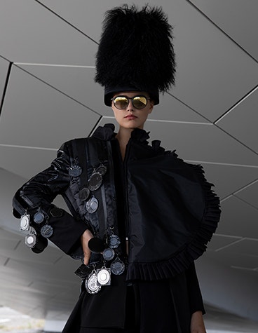 Female model posing with a hand on her hip, wearing all black and sunglasses from the Hoet Cabrio PR collection