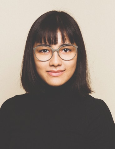 Younger female model smiling softly while wearing 3D-printed glasses