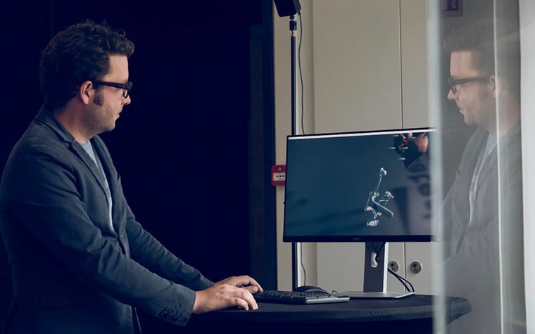 Man standing and looking at a 3D model on a computer