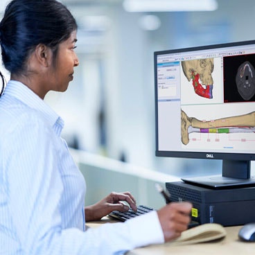 Mujer sentada frente a un ordenador utilizando el software de planificación médica