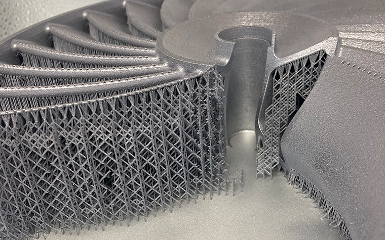 A metal, 3D-printed impeller model with fine support structures underneath and internally.
