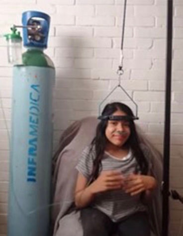 Patient sitting and smiling next to a large oxygen tank