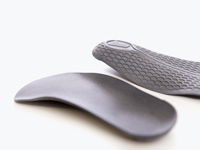 A pair of gray 3D-printed insoles made in PA 11 using Multi Jet Fusion.