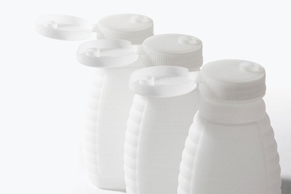 Row of honey bottles 3D printed in polypropylene with open snap lids