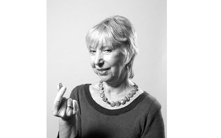 Gray-scale image of an older woman holding a personalized hearing aid