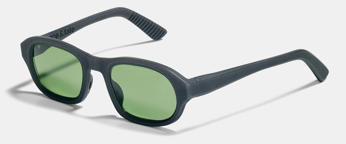 Schräge Produktabbildung der Ace & Tate Deadlift Tom Sonnenbrille in Grey Sun auf einem weißen Podest