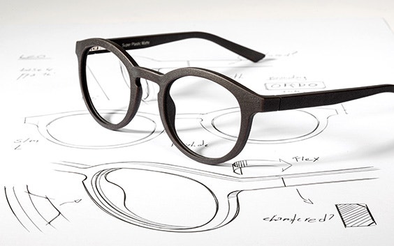 3D-printed eyewear frames lying on top of a drawn eyewear design