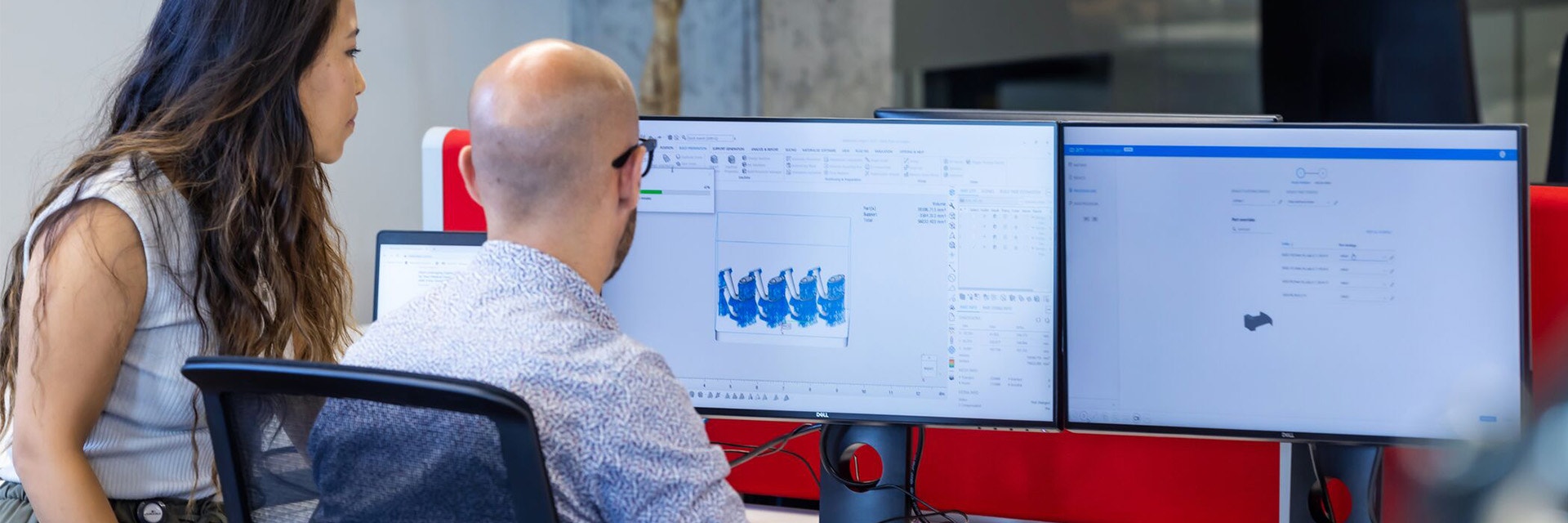 A man and woman looking at two computer screens with Materialise Nester software installed.