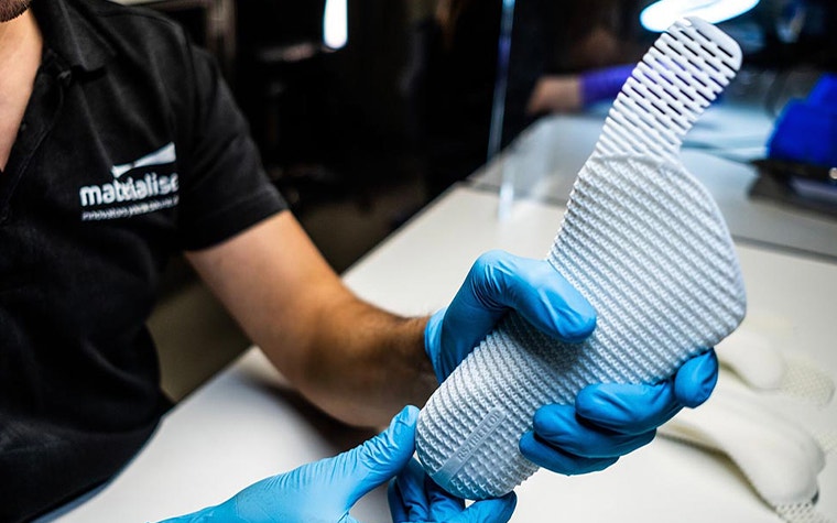 Materialise employee holding a 3D-printed insole in gloved hands