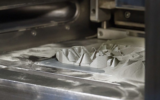 A series of 3D-printed parts being formed in a powder bed.