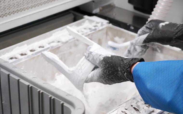 An application engineer from Extol removing the bespoke brace from 3D printing powder.