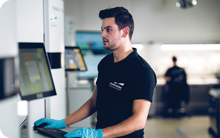 Materialise production team member looking at a screen on a 3D printer