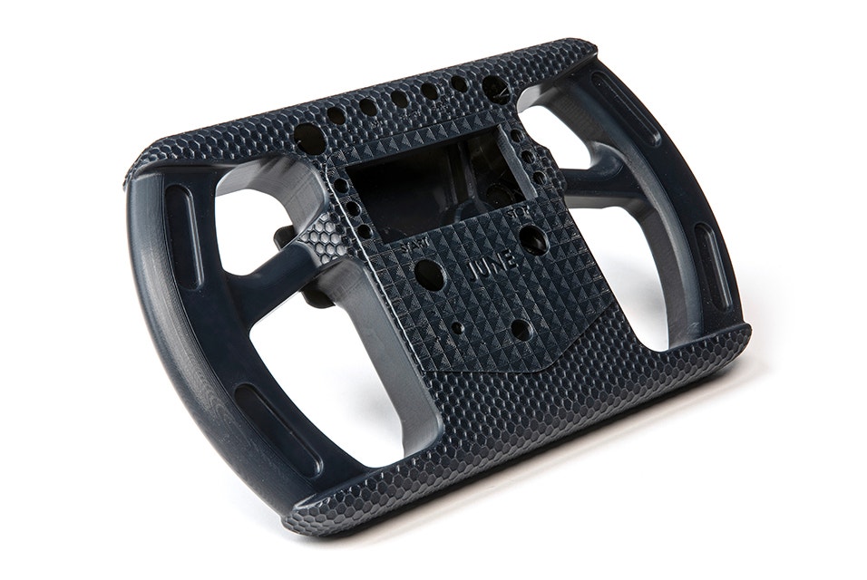 A black 3D-printed racing-style steering wheel made in Taurus using stereolithography.