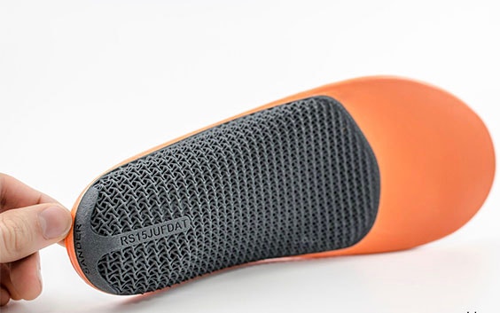Fingers holding up a 3D-printed, personalized insole