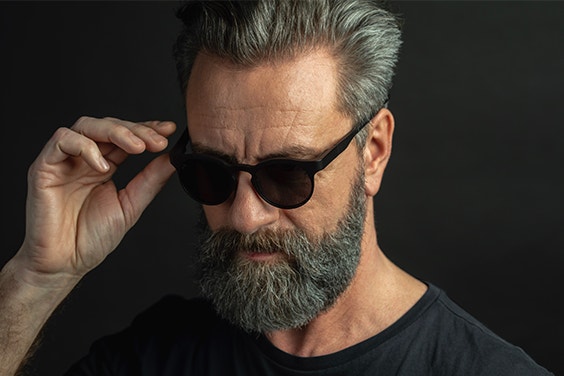 Male model holding Morrow Optics sunglasses on his face while looking downward