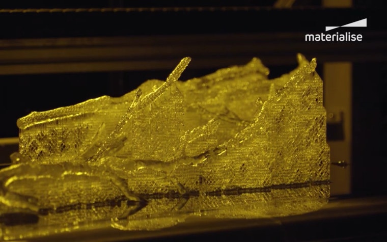 A 3D printed model of a tree, in transparent resin, on a Stereolithography printer's build platform. The branches are supported by latticed 3D printed support structures.