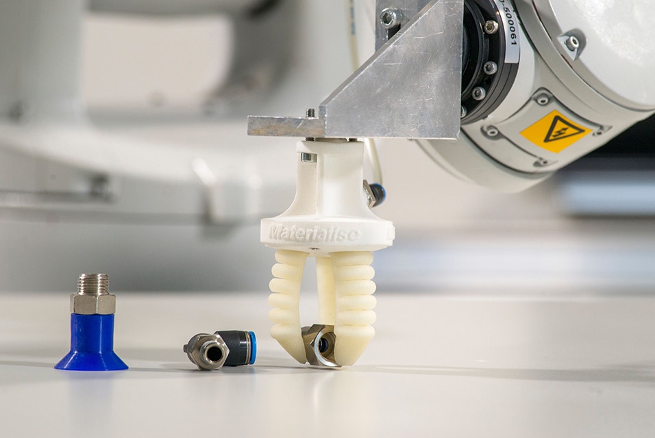 Una mano de pinza con cuatro dedos neumáticos flexibles de TPU impresos en 3D instalada en robots de una cadena de producción. La pinza está agarrando un pequeño tornillo a modo de ejemplo de tarea de agarrar y colocar en una línea de montaje.