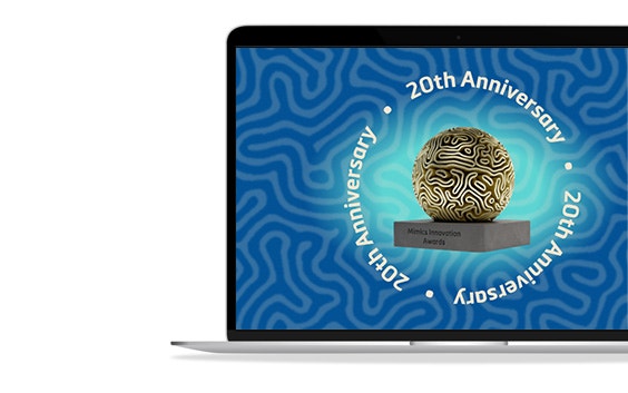 A laptop is on a white background. A blue screensaver is displayed on the laptop with the words "20th anniversary," and this sentence is repeated three times around a trophy with a golden sphere. The words "Mimics Innovation Awards" are on the trophy's base.