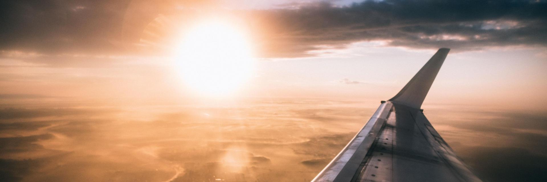 Vue d'un coucher de soleil et d'une aile d'avion depuis l'intérieur de l'avion
