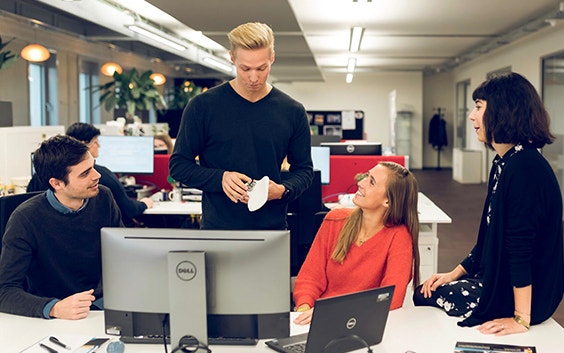 Group of Materialise employees speaking at a computer desk