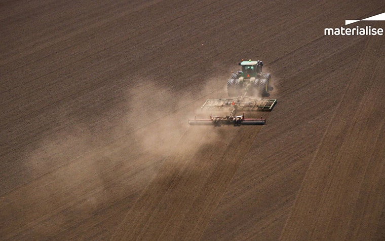 A farm machine crosses a dusty field